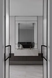 Modern minimalist bathroom featuring a marble sink and large mirror.