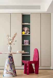 Modern home office featuring a colorful marble desk and a pink chair with a built-in shelving unit displaying toys and books.