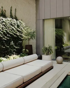 A minimalist outdoor seating area featuring neutral-colored cushions and a concrete sphere.