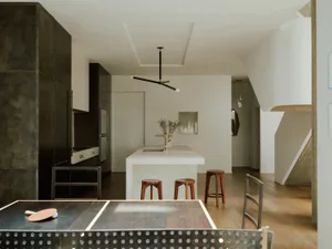 A minimalist residential kitchen with a concrete countertop and island, featuring black cabinets and a sleek, modern design.