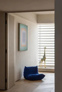 A modern contemporary interior space featuring a contemporary chair, neutral-toned walls, and a giraffe statue.