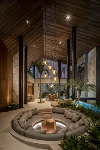 Modern living room with circular seating area, concrete floor, wood accents, and glass windows.