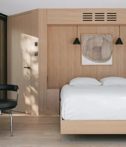 A minimalist bedroom featuring wooden interiors with a floating bed and hanging lamps.