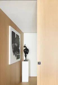 Modern minimalist interior with wooden walls, white column, and abstract black and white painting.