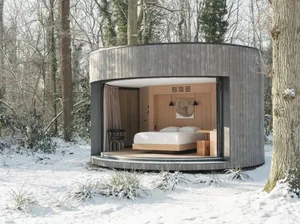 Modern bedroom with wooden walls, bed, and chair in a snowy forest setting