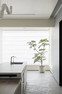 A modern kitchen with concrete countertops and glass elements.