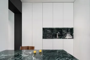 Modern kitchen featuring green marble countertops and white cabinets