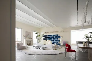 A modern living room with concrete flooring, minimalist furniture, and a large bookshelf.