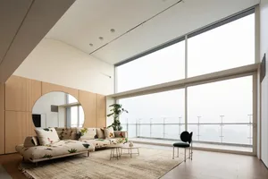 A contemporary living room with wooden walls, glass windows, and concrete flooring.