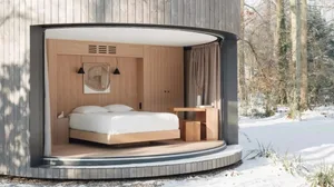 A modern minimalist bedroom with a wooden wall, white bedding, and a framed abstract art piece.