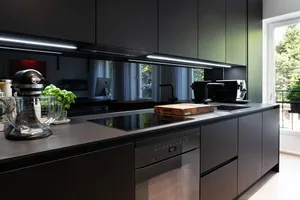 A modern minimalist kitchen with black cabinets and metallic finishes.