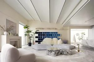 Minimalist residential room with white furniture and a blue accent wall.