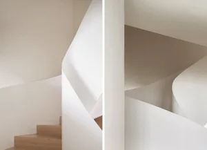 Modern, neutral-toned spiral staircase with smooth, curved walls.