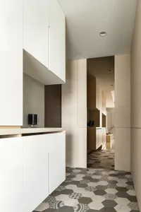 Modern residential kitchen with minimalist design, white cabinets, and marble walls