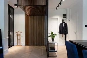 A modern dressing room with hardwood floors, a wooden panel wall, and a suit hanging on the wall.