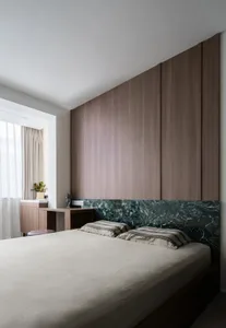 A modern minimalist bedroom with wood paneling and a marble headboard.