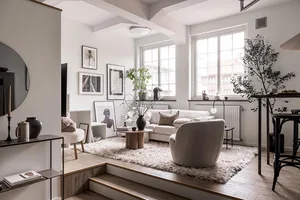 A minimalist living room featuring concrete walls and a white sofa with a plant on a wooden table.