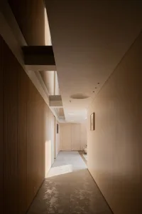 A minimalist corridor with neutral-toned walls, wooden panels, and a light-colored carpet.