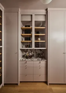 A minimalist wardrobe with glass shelves, marble countertop, and wooden drawers.