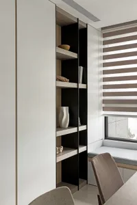 A modern bookshelf with wooden shelves, featuring decorative items such as a vase and books.