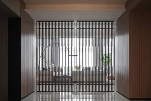 Modern interior design featuring a metal door with vertical bars and a curved handle.