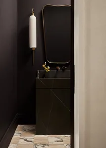 Minimalist bathroom featuring black marble walls and floor, with a black marble sink and gold fixtures.