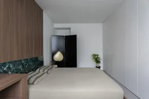 Modern bedroom interior with concrete walls and minimalist design elements.