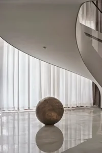 A modern interior with a floating wooden sphere on a reflective surface.