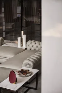 A modern living room with a corner couch upholstered in white leather, accompanied by a white marble coffee table.
