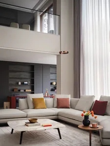 A modern living room featuring contemporary furniture, a large window with sheer curtains, and a cozy sofa adorned with color