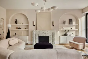 A modern minimalist living room with a concrete fireplace and floating shelves.