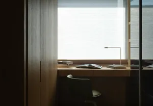 Minimalist office with a window view, wooden desk, and simple design elements.