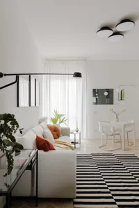 A minimalist living room featuring concrete furniture and a black and white striped rug.