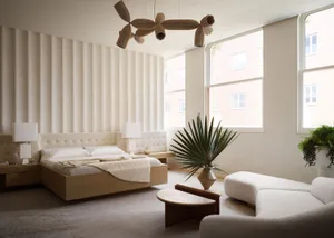 A minimalist bedroom with a white upholstered bed, wooden frame, marble coffee table, and large windows letting in natural li