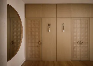 Modern interior design featuring a wooden closet with geometric patterns and brass sconces.