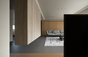 A modern living room featuring wood-paneled walls, a grey sofa, and a patterned rug.