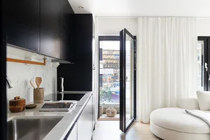 Minimalist kitchen featuring marble countertops, black cabinetry, and wooden accents