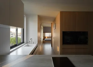 Modern minimalist kitchen with wooden cabinets and white countertops featuring a window view.
