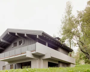 Modern residential house with wooden and concrete exterior, featuring clean lines and a flat roof.