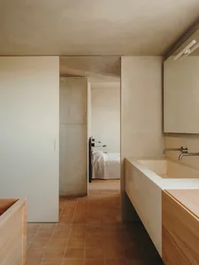 Industrial-style bathroom featuring a concrete sink and wall, with minimalistic design elements and warm lighting.