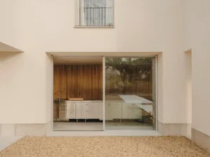 A minimalist kitchen with a large glass panel wall and wood cabinets.