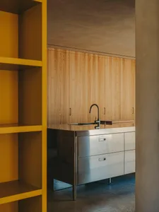 A minimalist kitchen featuring wooden cabinets and a stainless steel countertop.