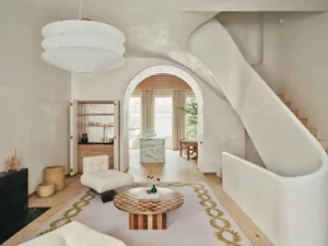 A modern interior design featuring a marble coffee table, a white fabric armchair, and a wooden floor.