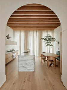 Modern residential kitchen featuring a marble countertop, wooden cabinets, and fabric curtains.