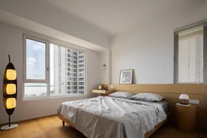A minimalist bedroom featuring a wooden bed and a tall, multi-lamp floor lamp.