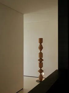 極簡風格的空間，白色牆面映襯著一件木製圖騰雕塑。