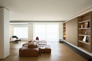 A modern living room featuring light-colored wooden flooring and furniture, with a contemporary sectional sofa and an open-pl