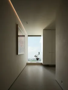 Modern, minimalist hallway with concrete flooring and white walls, featuring a Snoopy doll figurine.