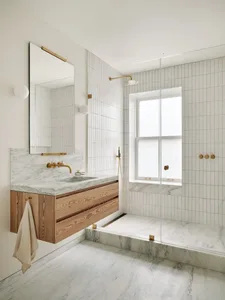 Modern minimalist bathroom with marble flooring, white walls, and wood vanity.