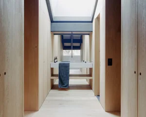 Modern bathroom interior with wooden walls, skylights, and white fixtures